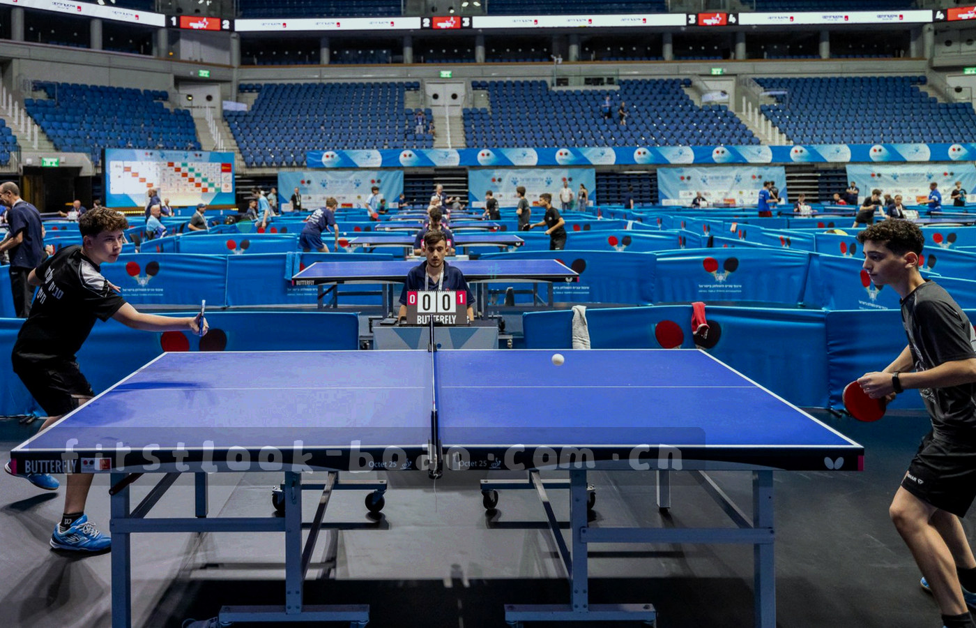 夜间工作台上的多块屏幕同时显示赛程表格与缺阵字段，桌面放着笔记本与冷光台灯